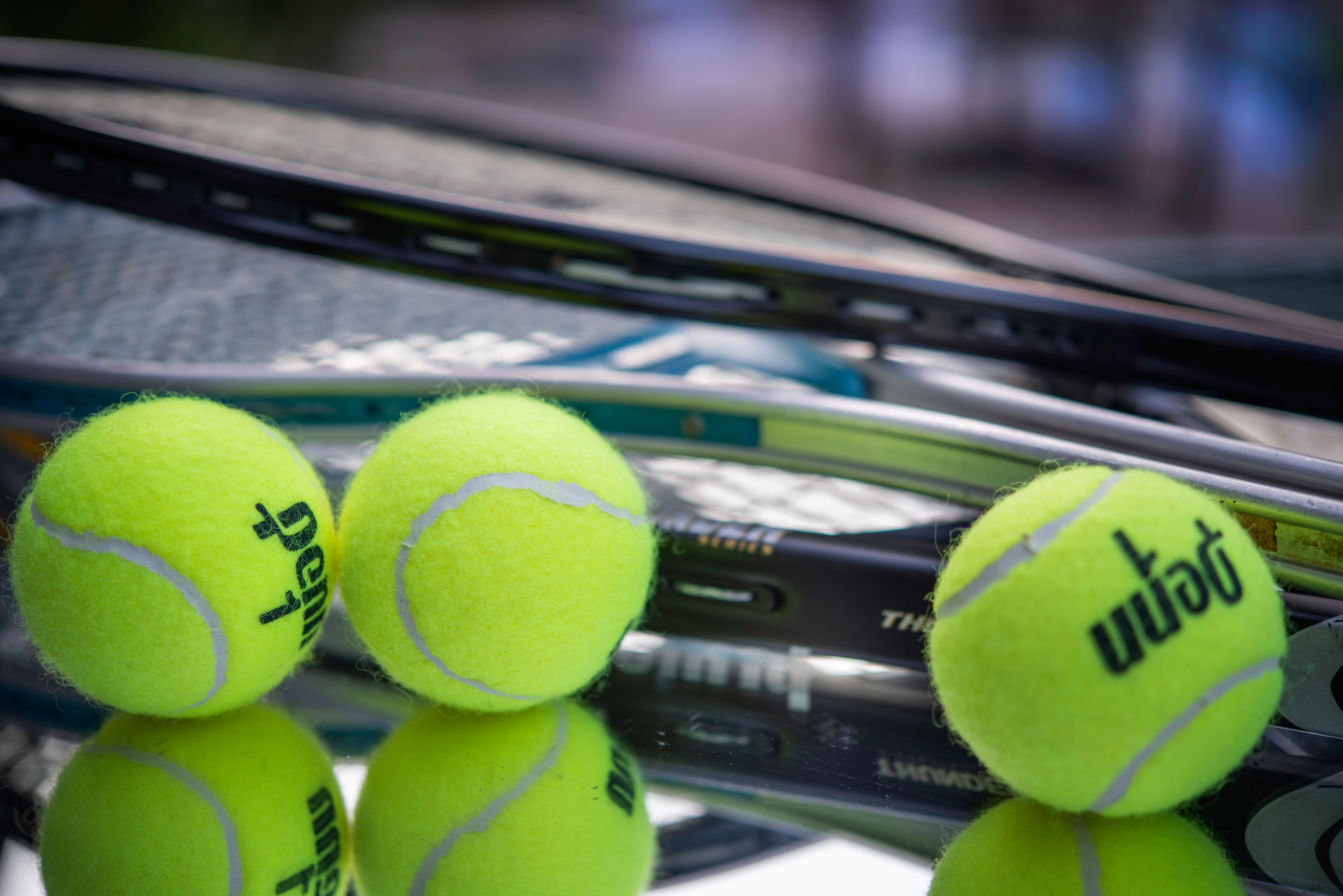 Pile of three tennis rackets surrounded by three tennis balls